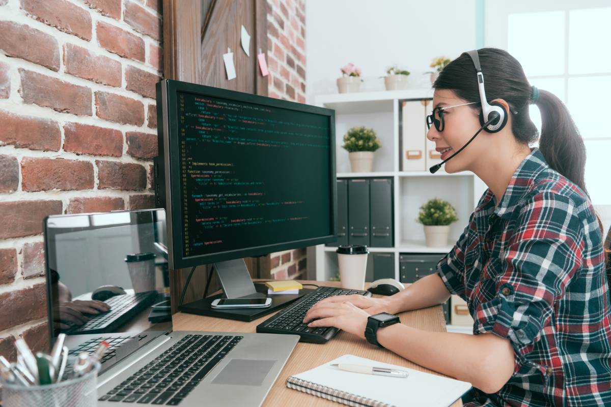 A woman working from home using a laptop and a headset