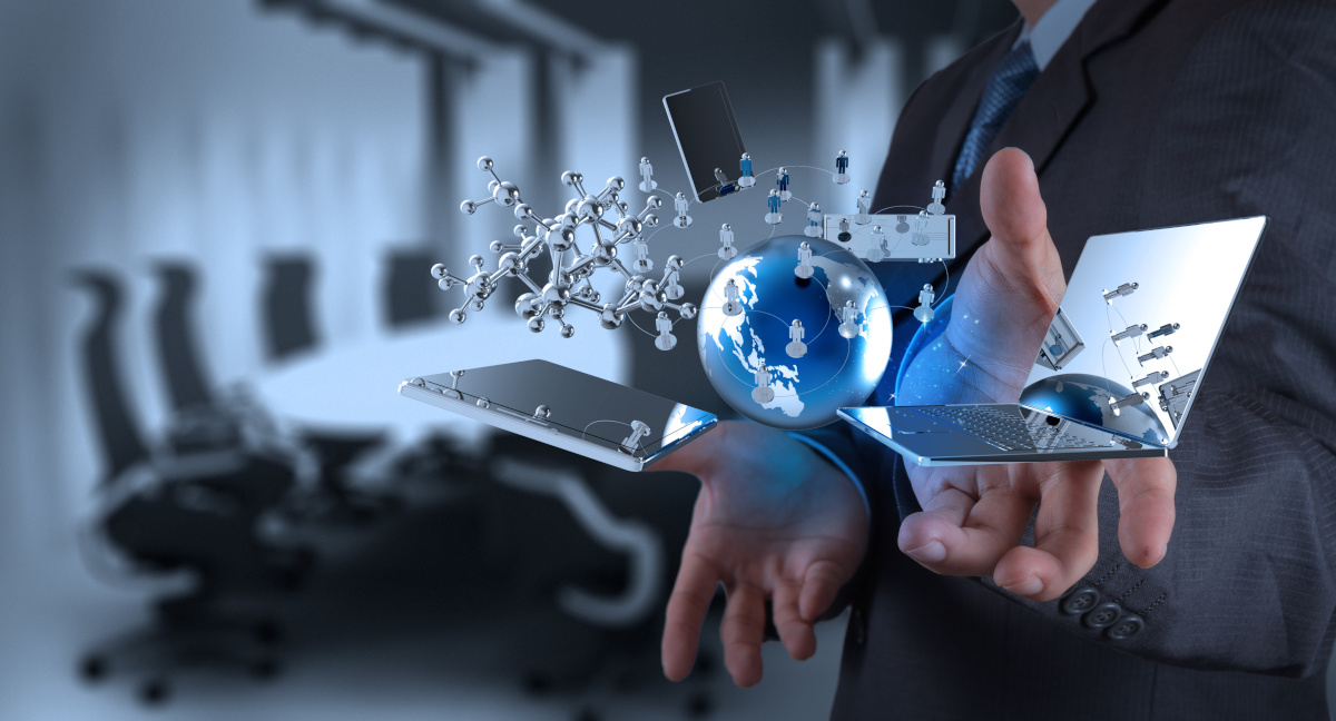 A cellphone, globe, and laptop hovering above a businessman's hands