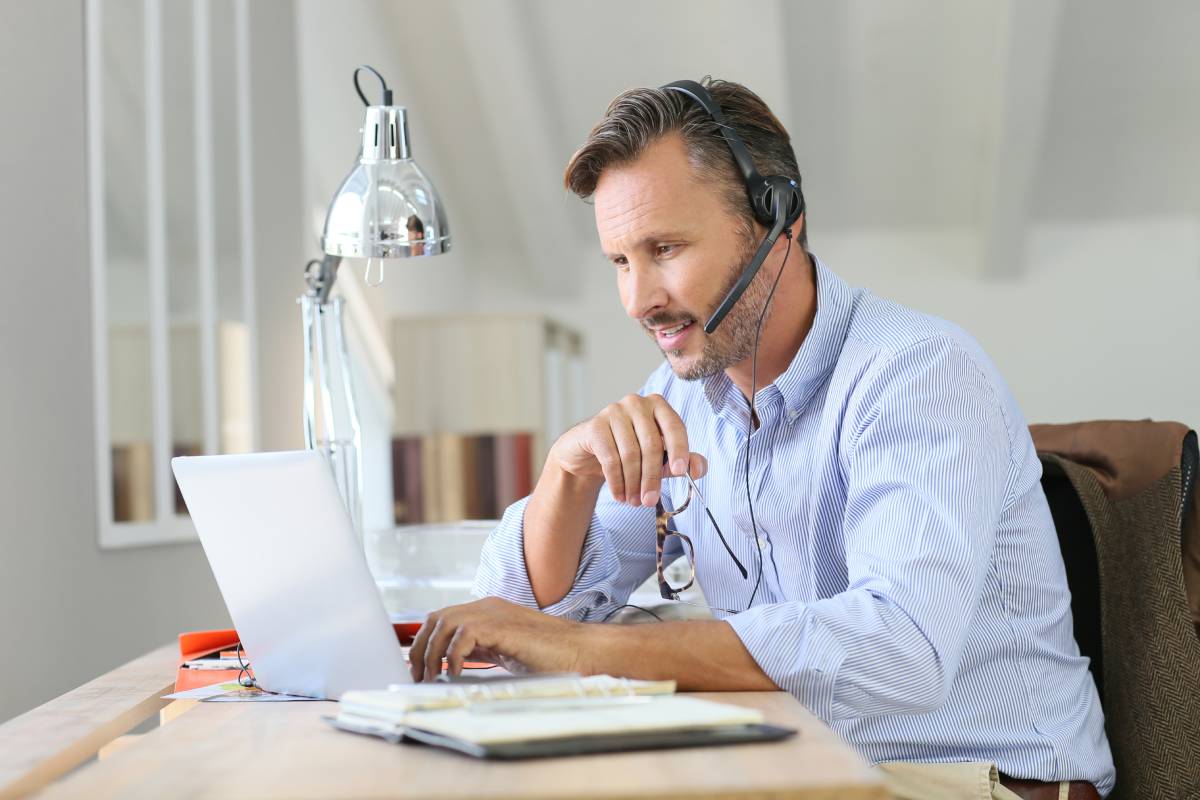 A man working from using a headset and a laptop