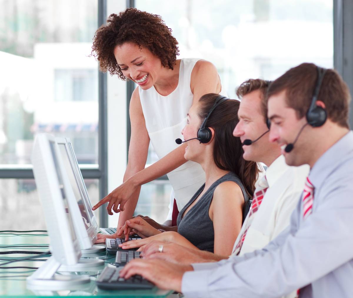 Help desk employees working while using a laptop and headsets