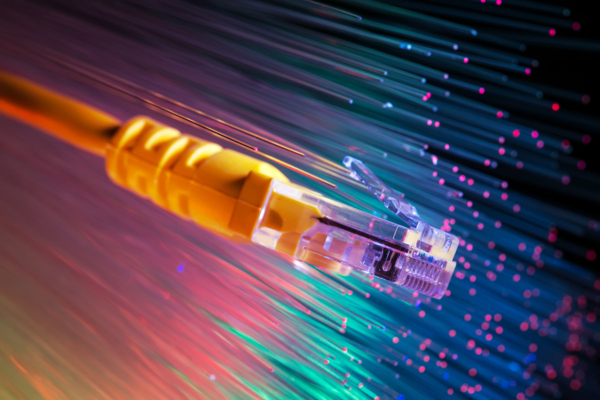 Orange network cable with background of fiber optic cables.