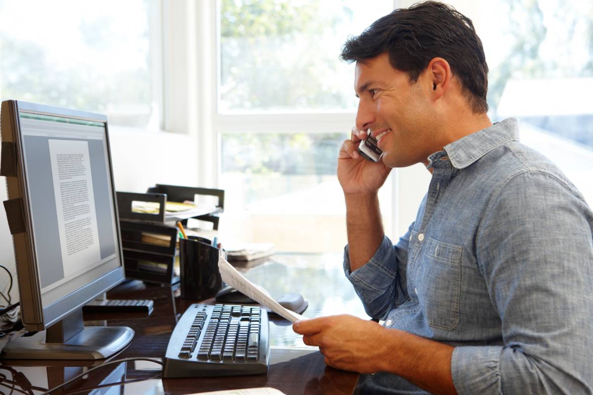 A man working at his computer while talking on the phone