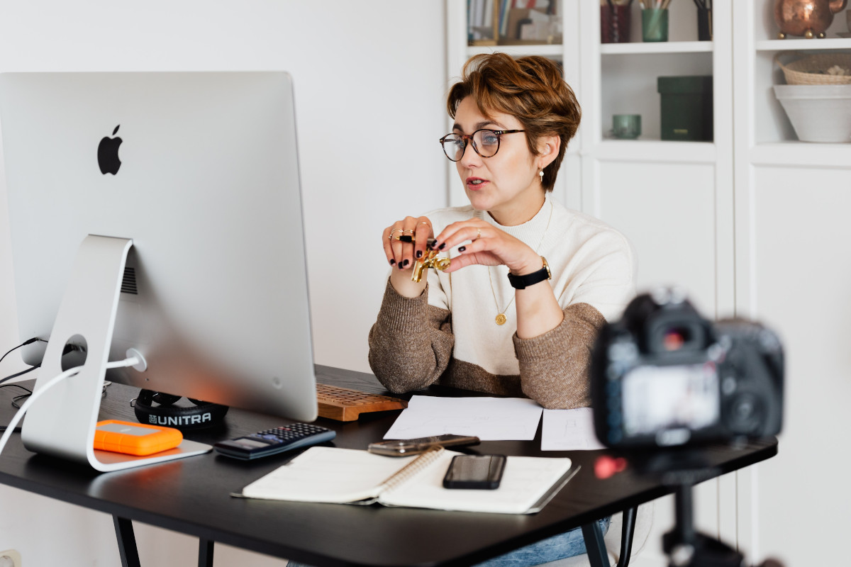 A woman wearing glasses using her computer to video conference with colleagues