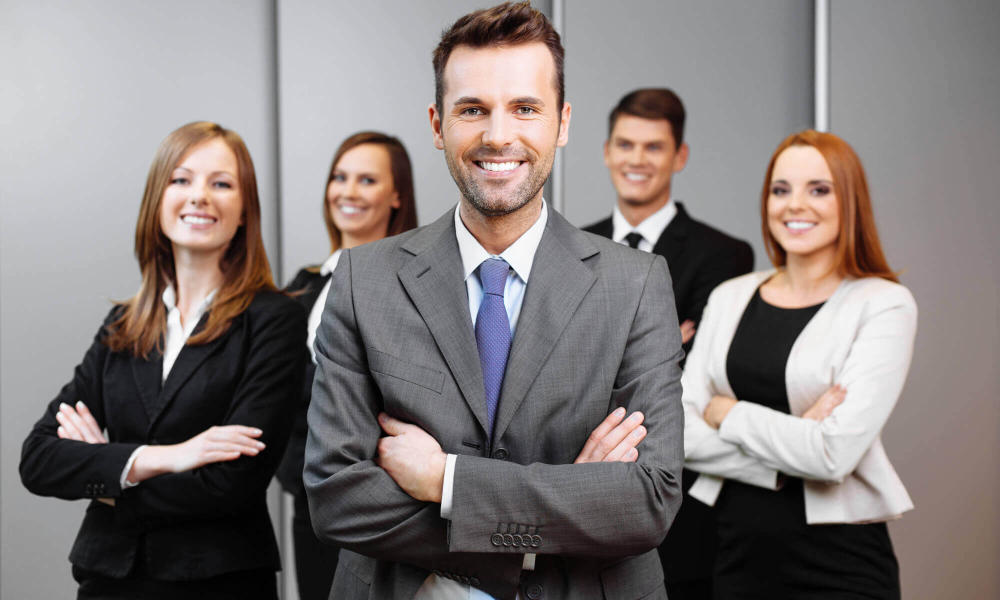 Group of 5 smiling business people looking towards the viewer