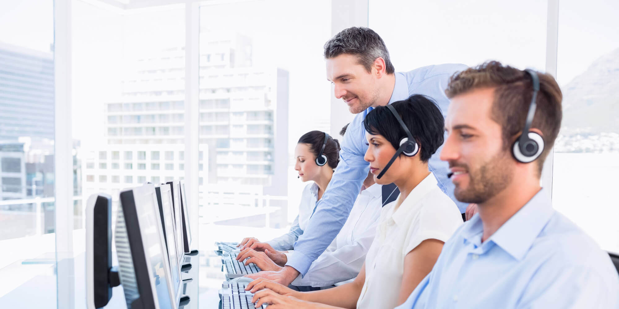 Call center employees wearing VoIP headsets and working on computers