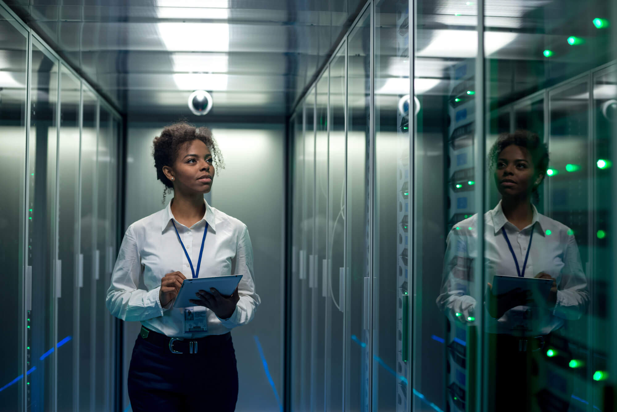 Female data technician in server room holding a clipboard 