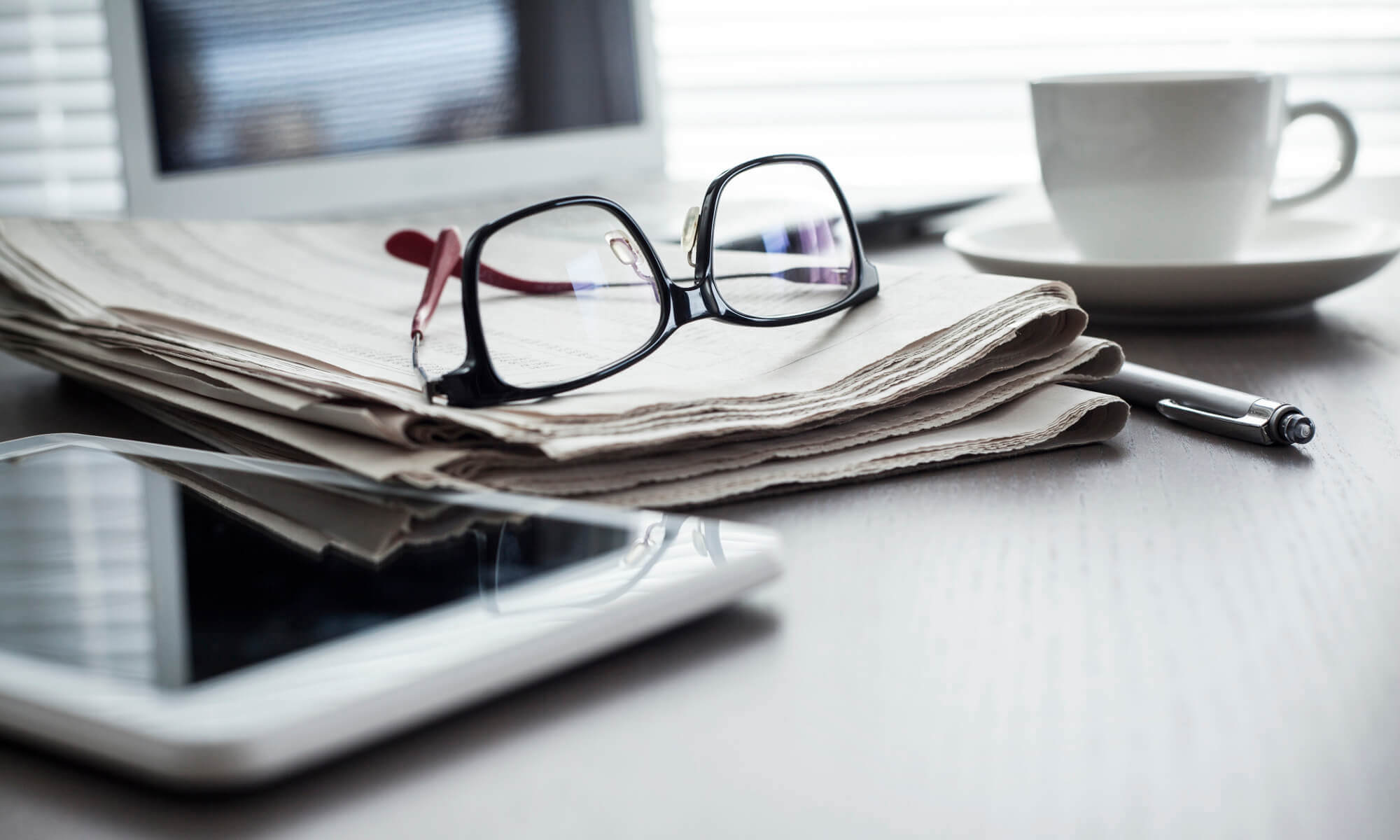 Pair of glasses resting upside down on a newspaper