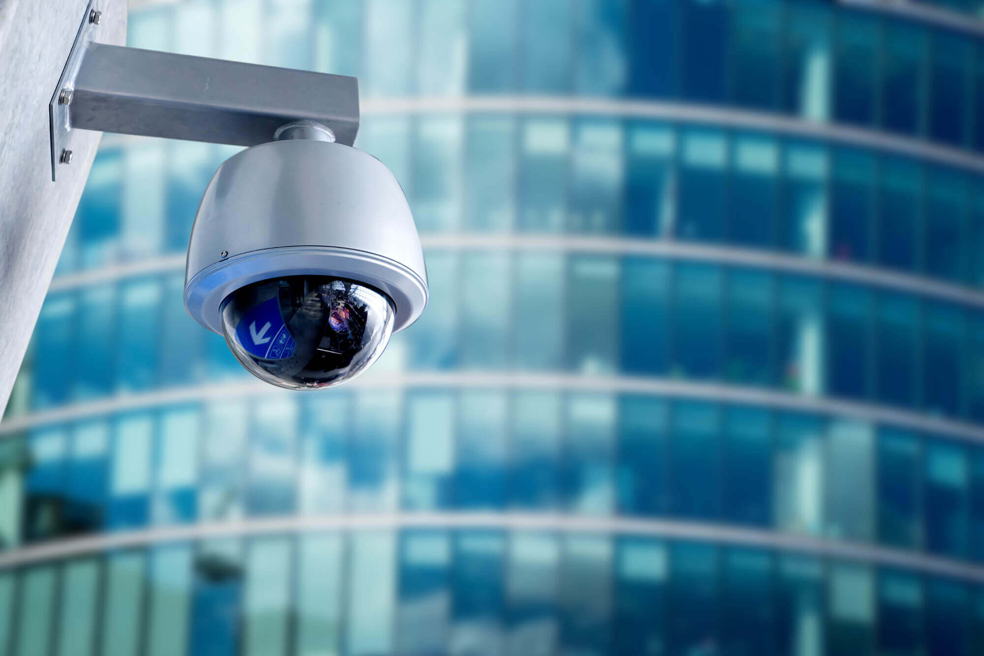 Video surveillance camera against a blurred background of a modern highrise building